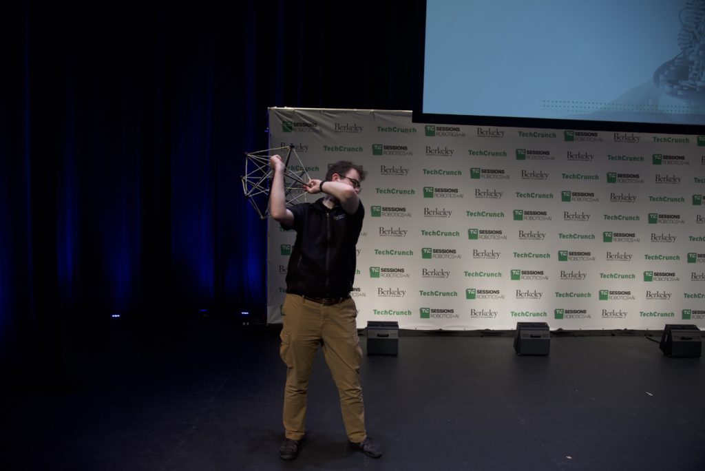 Lead Mechatronics Engineer Throwing Squishy Stationary Robot Across the Stage.